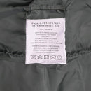 Close-up of MIL-TEC N3B aviator parka label showing material and care instructions on olive fabric background