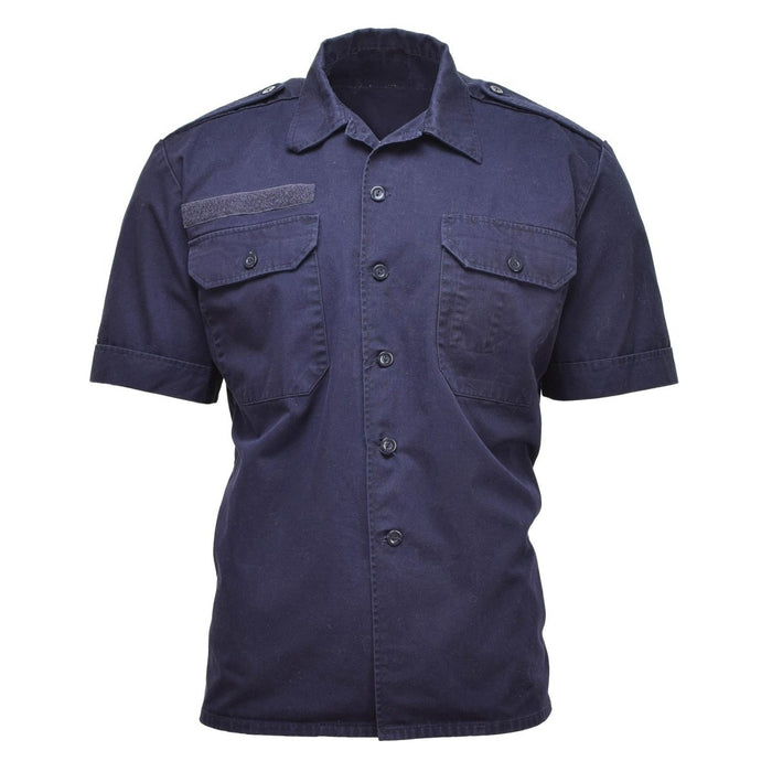 Camisa excedente militar holandesa de manga corta de color azul liso con botones al frente, bolsillos en el pecho y charreteras en los hombros.