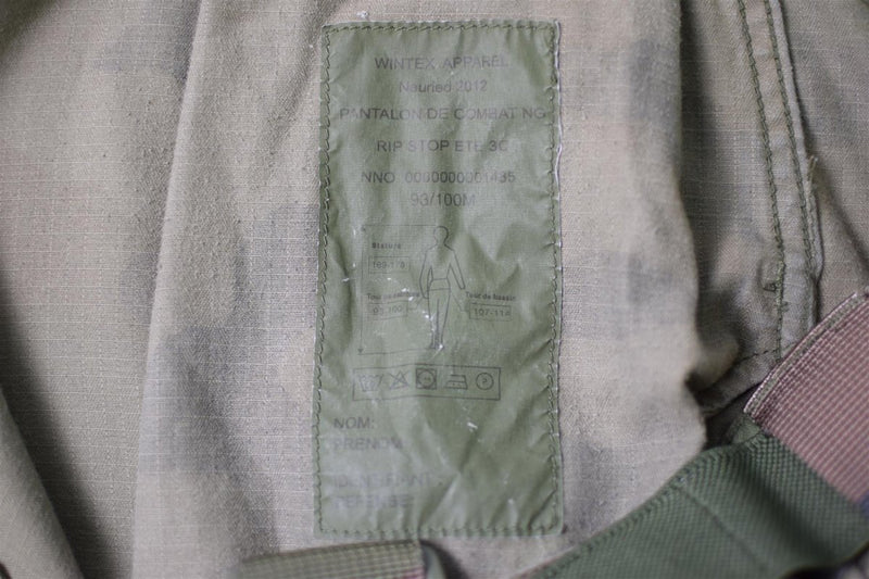 Close-up of label inside French army combat pants made from durable ripstop fabric with care instructions.