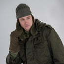 Man wearing genuine German Army olive drab winter pile cap with ear flaps and matching cold weather military jacket