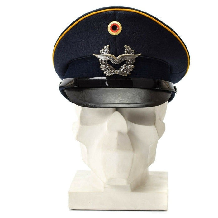 Gorra azul vintage con visera de las fuerzas aéreas de la Luftwaffe alemana con insignia militar y ribetes amarillos en un busto blanco