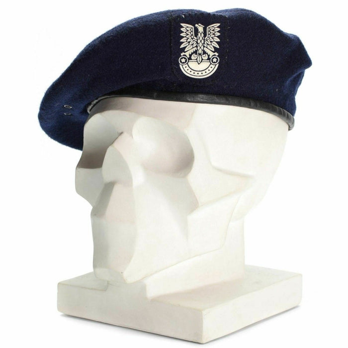 Auténtica boina azul militar polaca con emblema en la cabeza de maniquí blanco, que simboliza el honor y el servicio.