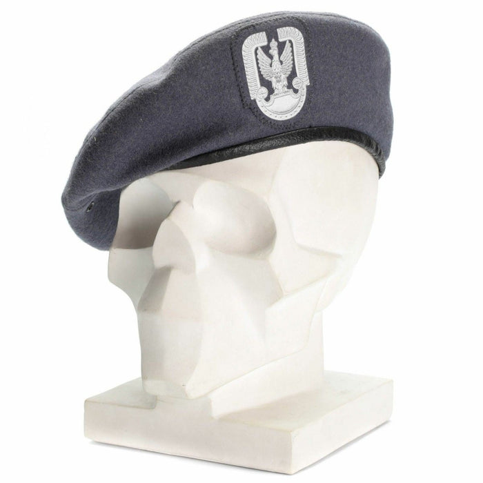 Boina de paracaidista militar polaco de lana gris con insignia frontal, exhibida sobre una cabeza de maniquí blanca.