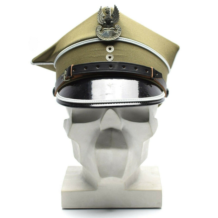 Auténtica gorra de oficial militar polaco con escarapela de águila y visera de cuero exhibida en una cabeza de maniquí blanca.