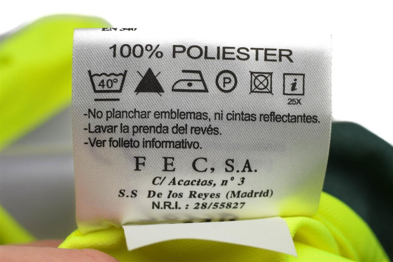 Close-up of care label on yellow polyester reflective Spanish Civil Guard polo shirt with washing and ironing instructions.