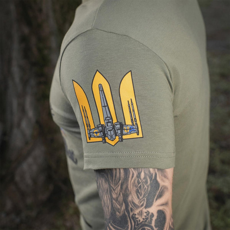 Close-up of olive green M-TAC military style t-shirt sleeve with yellow Ukrainian flag emblem and tattooed arm visible