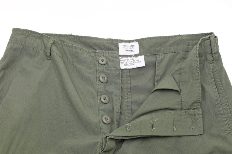 Close-up of olive drab Mil-Tec U.S. Army M64 Vietnam jungle style combat pants with button fly and adjustable waist.