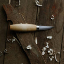 MORAKNIV Woodcarving 120 carbon steel knife with wooden handle on wood with wood shavings around it.