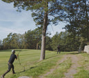 Two people using the Nordic Pocket Saw to trim a high tree branch outdoors in a forested area.