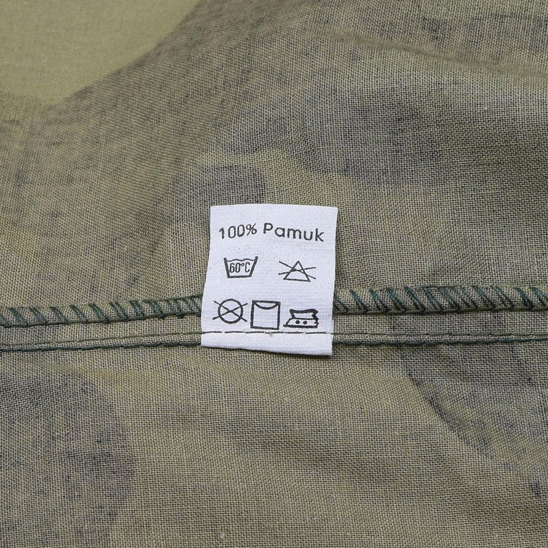 Clothing care label on Croatian woodland camo BDU shirt showing 100% cotton and washing instructions.