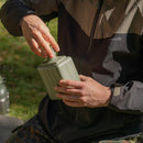 Person opening the lid of an original Yugoslavian military surplus canteen mess kit outdoors.