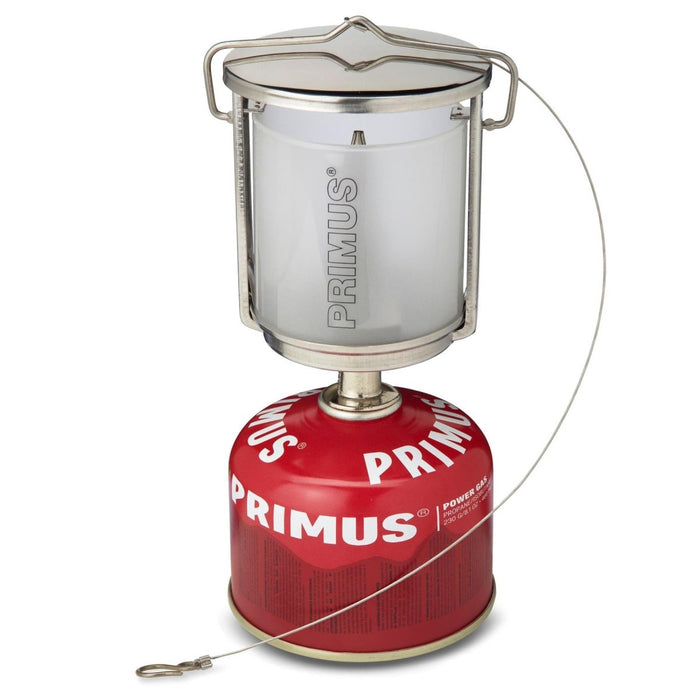 Linterna de camping portátil Primus Mimer con cuerpo de acero inoxidable y cristal esmerilado sobre depósito de gas rojo.
