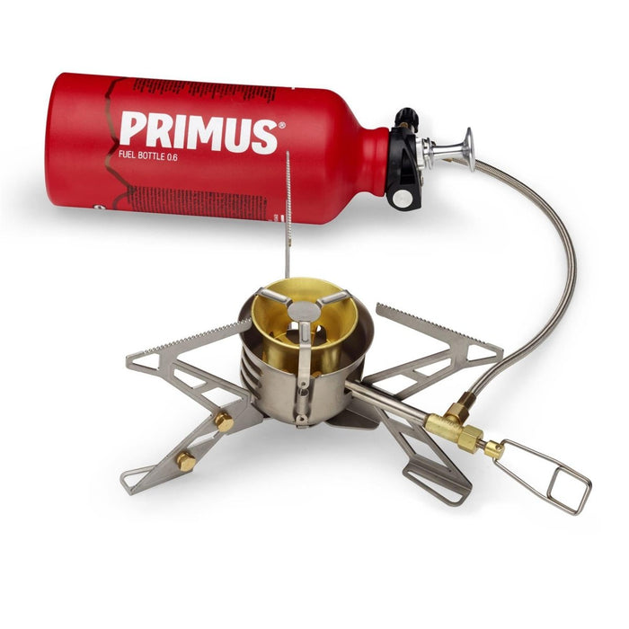 Estufa de camping multicombustible Primus OmniFuel II con botella de combustible roja, soportes de acero inoxidable y manguera de combustible para cocinar al aire libre.